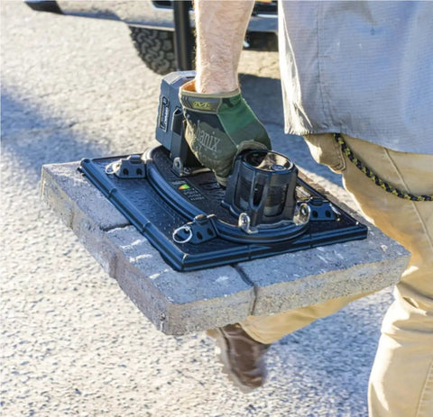 Worker using high-flow cordless vacuum lifter for pavers and porous materials with LED pressure display to lift dry cast pavers.