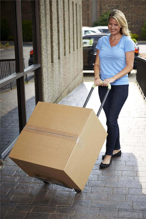Woman using ✝️ COSCO Shifter Multi-Position Folding Hand Truck and Cart, 300 lb. Weight Capacity, Green, 12222PBG1E to move a large box