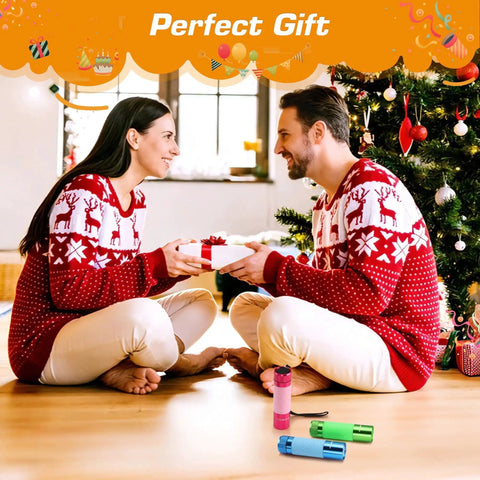 Couple exchanging gifts wearing matching sweaters next to Christmas tree with three pack glow in the dark aluminum mini flashlights.