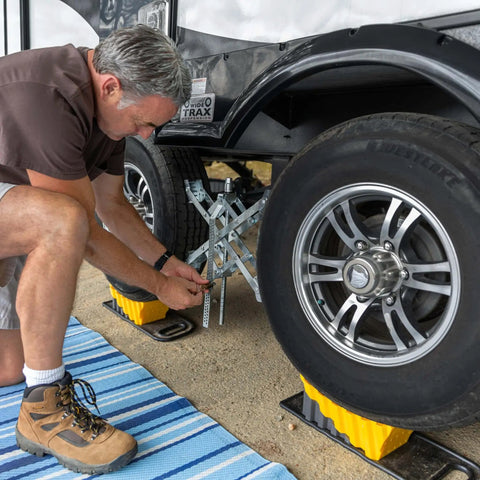 Man using Curved Camper Leveler And Wheel Chock For RVs And Trailers Up To 30,000 Lbs By Camco under tire, drive on leveling