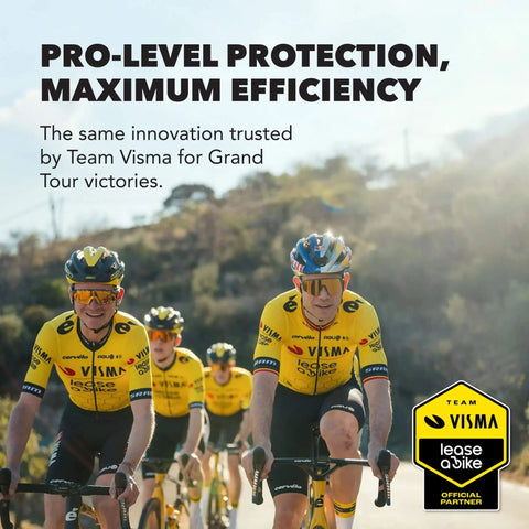 Cyclists wearing yellow Team Visma jerseys riding bikes in a group on a road with trees in the background.