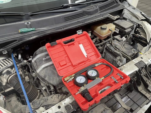 Amazon HFS Cylinder Leak Detector kit in red case with two gauges and hoses on car engine bay