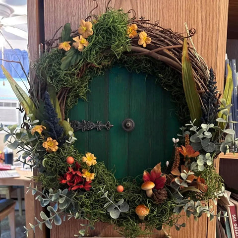 Decorative wreath with flowers and greenery on a wooden door, indoor setting.