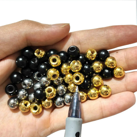 Hand holding assorted M4 thread cap nuts including silver steel ball screw caps for furniture lighting, smooth metal finish.