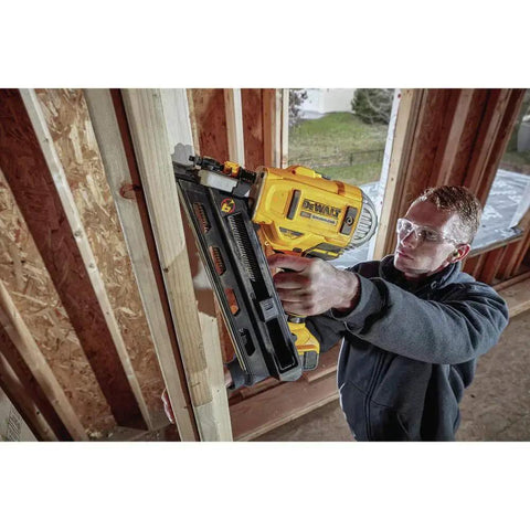 Man using DEWALT 20V MAX XR Framing Nailer to drive nails into a wooden frame on a construction site