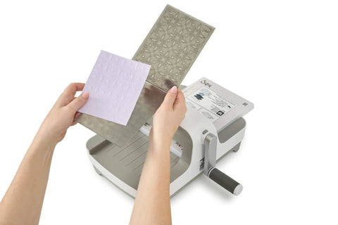 All In One 6 Inch Die Cutting And Embossing Machine Starter Kit For Crafters Includes Cutting Dies Embossing Folder Cardstock And Accessory Pack Compatible With Sizzix Big Shot For Scrapbooking And DIY Card Making showing die insertion