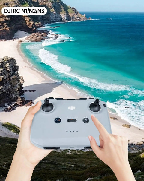 Pair of hands holding DJI RC-N1 remote controller with ocean view backdrop