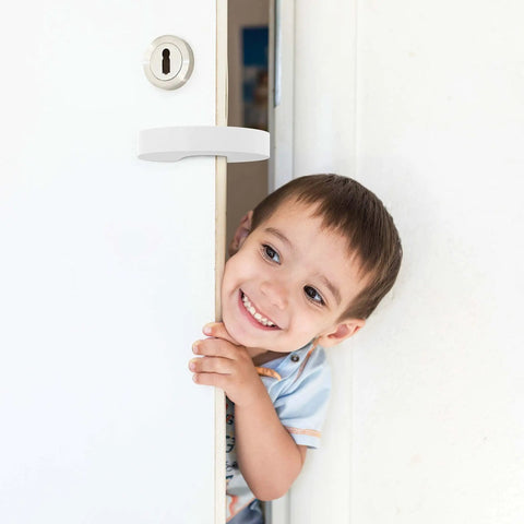Child standing in doorway protected by Door Pinch Guard And Door Stopper Six Pack With Soft Foam Safety Guards To Keep Doors Open, Prevent Finger Pinches, And Protect Kids And Pets With Safe Home Door Barriers For Everyday Use.