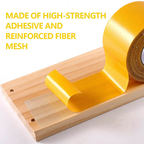 Yellow double sided fabric tape on wooden surface, showcasing heavy duty adhesive and reinforced fiber mesh.