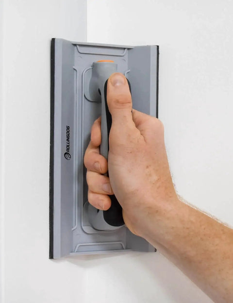 Person using Drywall Corner Sander Kit With Two Sided Pad And Six Sandpapers Included to smooth a wall corner