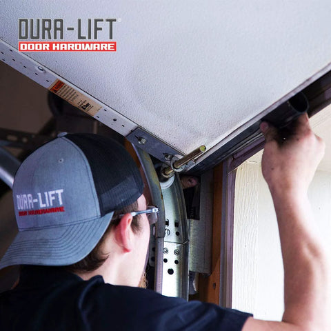 DURA-LIFT garage door rubber weather seal being installed on 8' wide doors; installer wearing a DURA-LIFT cap.