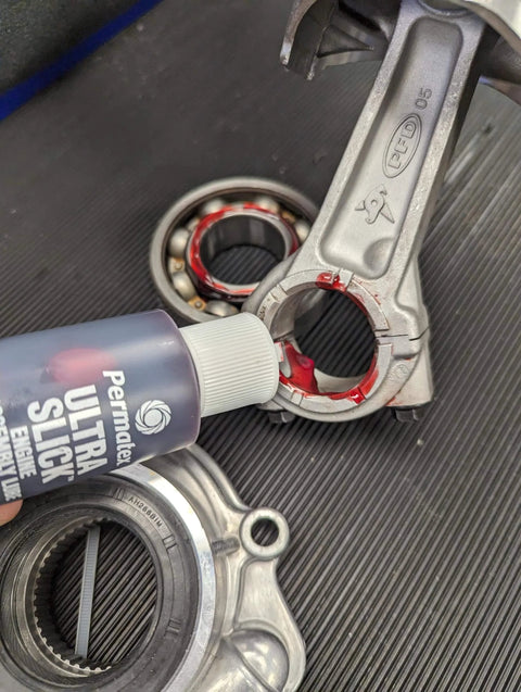 Permatex 81950 Ultra Slick Engine Assembly Lube, 4 oz., Red applied to metal engine component.