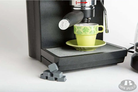 Self Adhesive Bumper Feet 0.780 In By 0.380 In Black Square Polyurethane Pads next to an espresso machine and cup