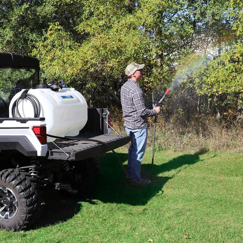Man using Everflo 12V On-Demand Diaphragm Sprayer Pump - 5.5GPM, 60 PSI, Quick Attach Ports on a utility vehicle in a grassy area