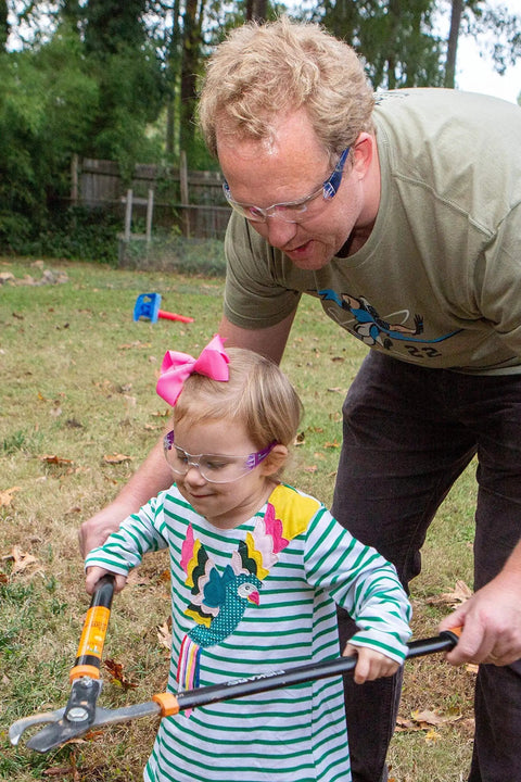 Adult and child wearing UV Protection Safety Goggles with 99 Percent UV Impact Resistant Clear Lenses while using gardening tools outdoors.
