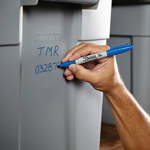 Hand using fine point permanent markers deliver bold, precise lines with quick-drying, odorless ink that resists fading and is waterproof on plastic bin.