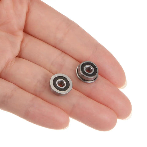 Hand holding two Flanged Ball Bearing F6232RS 3x10x4mm Double Sealed Chrome Steel ABEC1 Bearings, showing rubber seals.