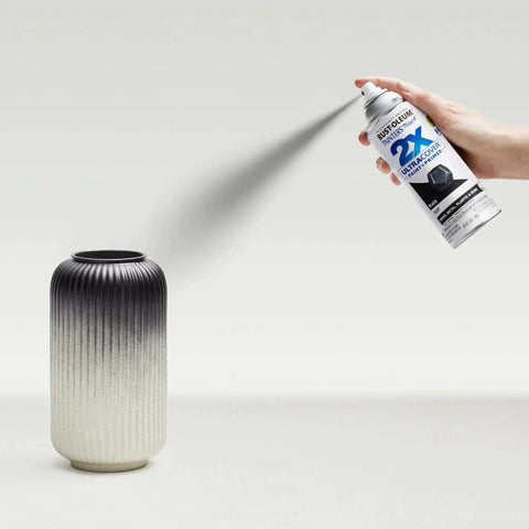 Person using Painter's Touch 2X Ultra Cover Spray Paint In Flat Black on a decorative ceramic vase, illustrating indoor DIY application.