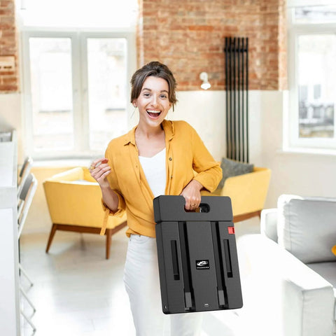 Woman holding a ✝️ Folding Hand Truck, 500 LB Heavy Duty Luggage Cart, Utility Dolly Platform Cart, black, in a modern room.