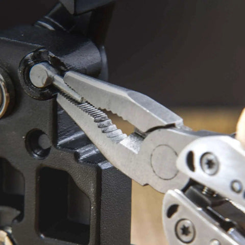 Close-up of Framework Mini 11 In 1 Multitool open frame with needle nose pliers gripping a metal part, showcasing detailed tool design.