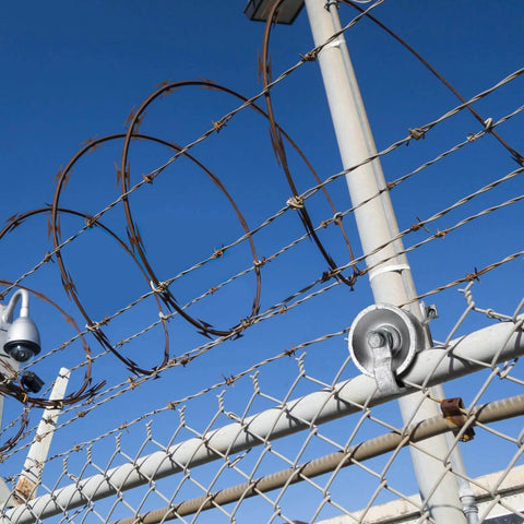 5" Pipe Track Wheel Galvanized installed on 1 7/8" chain link fence gate frame under blue sky with barbed wire