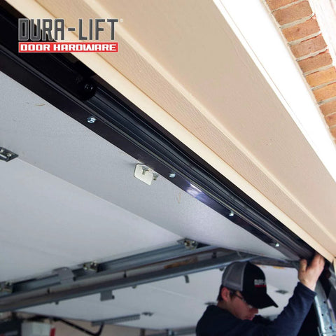 DURA-LIFT garage door rubber weather seal along bottom edge; installer working on door hardware.