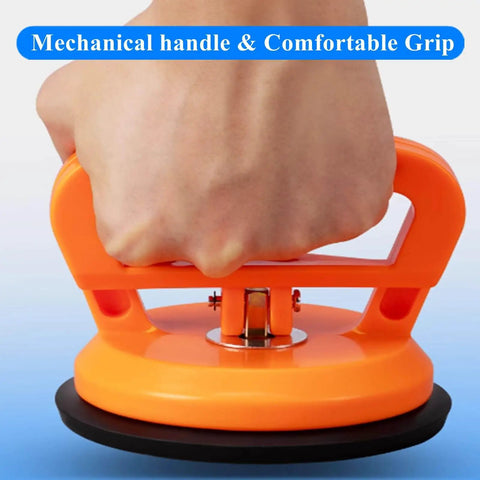 Close-up of hand holding Two Pack Glass Vacuum Suction Cups Lifter Dent Puller Tool, orange handle with rubber chassis for glass surfaces