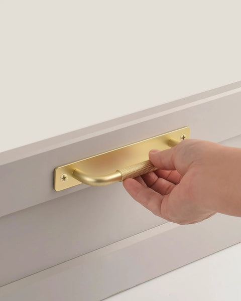 Close-up of hand pulling 2 Pack Gold 7 Inch Barn Door Handle For Sliding Closet Doors With Backplates and Drawer Pulls, installed on a surface.