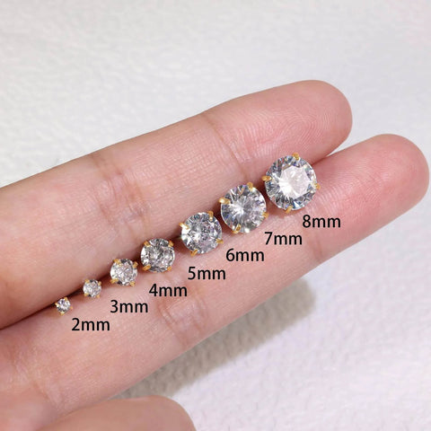 Variety of sizes of cubic zirconia stud earrings including 2mm gold titanium earrings for Toddler. Earrings arranged on a hand.
