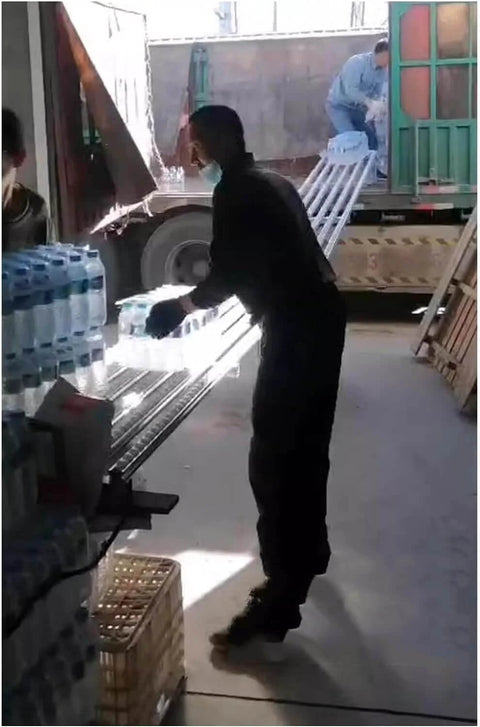 Workers unloading bottles using Light Duty Gravity Conveyor Slides With ABS Plastic Roller System And Stainless Steel Frame Two Slide 200 Cm Long.