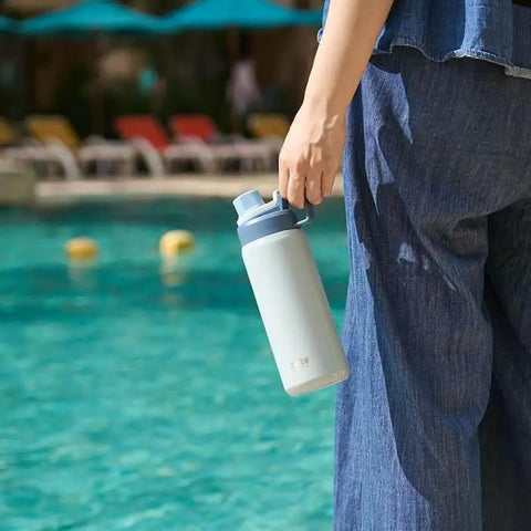 Person holding Insulated Stainless Steel Water Bottle With Spout Lid And Easy Grip Handle For Sports On The Go Vacuum Insulated Bottle