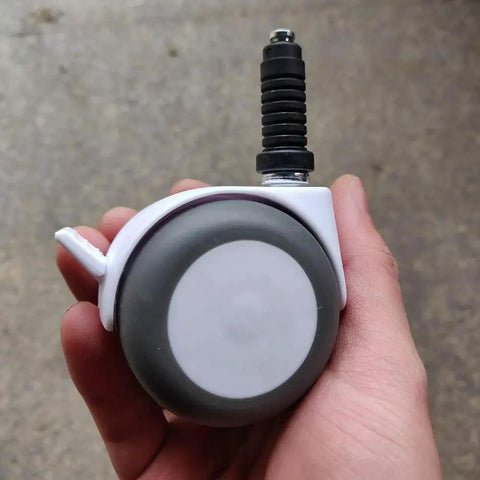 Hand holding a plastic caster with a stem grip, showing a single wheel from the 20 Pcs Plastic Round Caster Wheel Socket Sleeve Caps set.