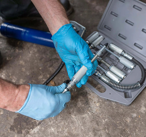 Mechanic using Versatile Grease Lubrication Adapter Kit With 12 Inch Hose And Quick Connect Couplings, Rubber Tip And Needle Nozzles, 360 And 90 Degree Couplers for precise lubrication