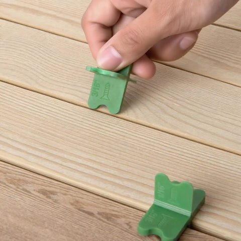 Hand using 4 In 1 ABS Deck Spacer Tools Set For Accurate Deck Gaps With Four Sizes One Sixteenth One Eighth Three Sixteenths And One Quarter Inch Pro Grade Reusable Green 9 Pack For Pressure Treated And Composite Decking on wood boards.