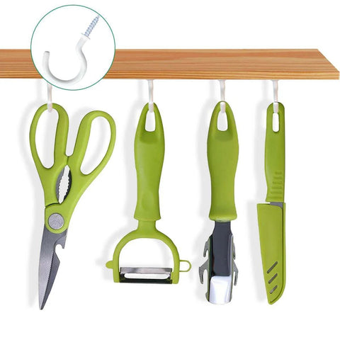 Green kitchen utensils hanging on hooks under a wooden shelf, including scissors, peeler, bottle opener, and knife.