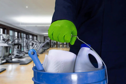 Person wearing Green Nitrile Latex Free Gloves 8 Mil Heavy Duty Raised Diamond Texture holding cleaning supplies bucket in gym