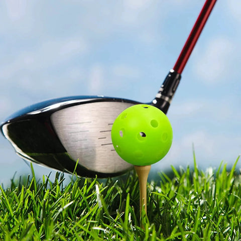 Golf club hitting green plastic practice golf ball on tee, part of 50 Pack Plastic Golf Balls Practice Limited Flight Golf Training Ball Hollow Swing Practice Indoor Balls with Mesh Drawstring Bag for Backyard Driving Range or Outdoor (Green).