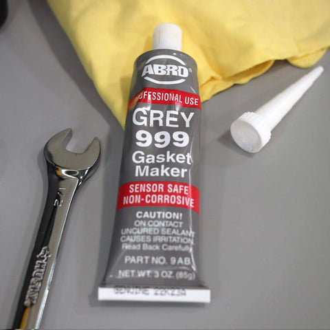 Heavy Duty High Temp RTV Silicone Sealant And Gasket Maker 650 Degrees F OEM Specified Sensor Safe Non Corrosive Neutral Cure Low Odor 3 Oz Tube Grey Sealant For Head Gaskets Oil Water Anti Freeze Resistant on table with wrench.