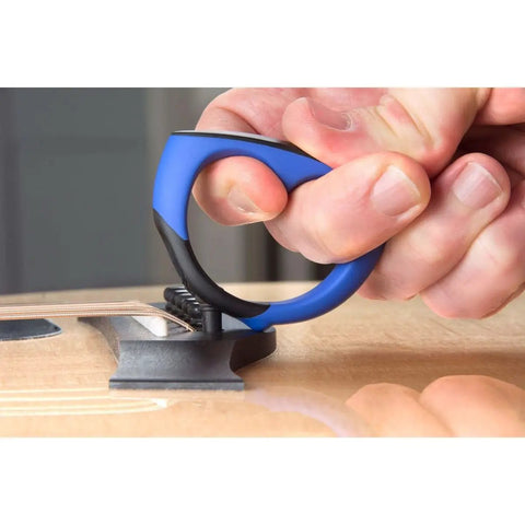 Close-up of All-In-One Guitar String Changing Kit with winder in use on an acoustic guitar, silent scratch-free grip design.