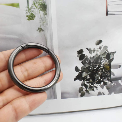 Hand holding a large 3-inch round carabiner clip in gun black, used for keychains, bags, purses, and DIY charms, crafts making.