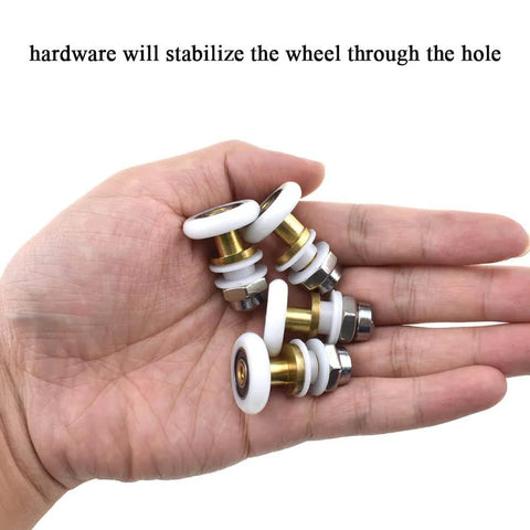 Hand holding 23mm diameter brass shower door wheels with nylon rollers and stainless steel screws