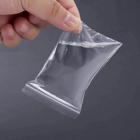 Hand holding a clear small plastic bag from 300 PCS Small Plastic Bags Set In 3 Sizes 2x2.5in, 2.2x3in, 3x3.5in Resealable Clear Poly Bags.