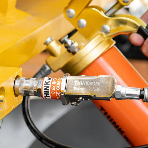 Hands Free Lock On Grease Gun Coupler With Cleaning Tool, 14000 PSI Quick Release, shown in use on machinery with 5/8 inch size.