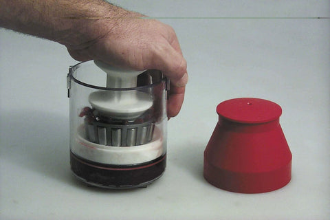 Hand holding the 34550 Handy Packer Bearing Packer with red cap beside, used for wheel maintenance.