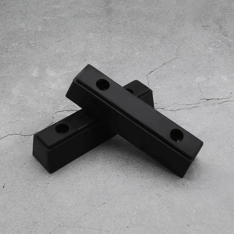Two black Beefy Rubber Bump Stop Buffer For Heavy Doors And Vehicles Anti Collision Block For Trucks Trailers Motorhomes Steel Doors Industrial Use 210x50x50mm on concrete surface.