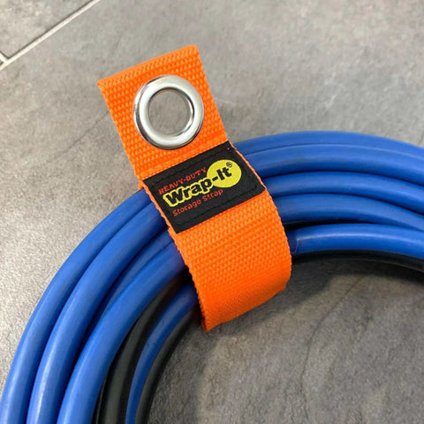 Close-up of blue cable secured with Heavy Duty Wrap It Storage Strap 10 Inch Blaze Orange for garage organization.