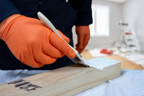 Person painting wood while wearing Hi Vis Orange Nitrile Gloves Raised Diamond Texture 8 Mil Large Box Of 50