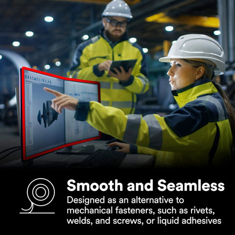 Workers in safety gear discussing designs on a monitor in an industrial setting.