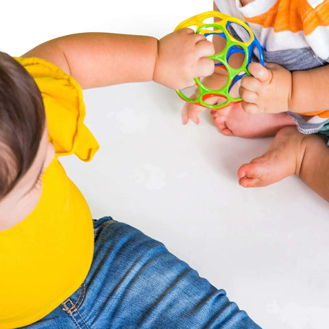 Infants playing with Bright Starts Oball Easy Grasp Classic Ball BPA-Free Infant Toy in red, yellow, green, blue, Age Newborn and up, 4 Inches.
