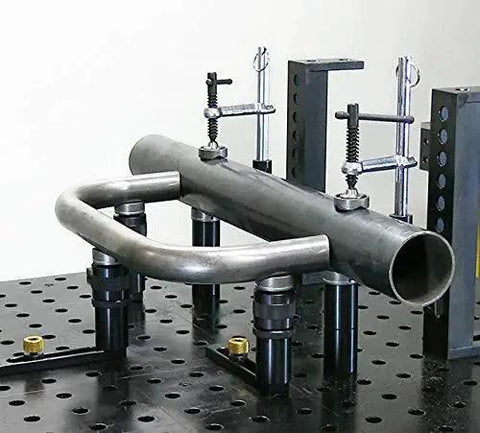 Inserta Clamp For Eight And A Half Inch Capacity By Build Pro UEN5200 holding metal pipe securely on a perforated table.